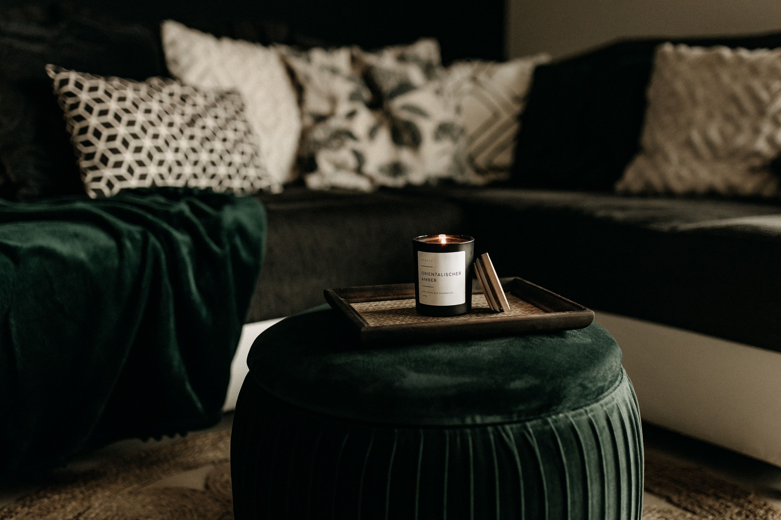 Duftkerze im schwarzen Glas aus Sojawachs auf einem Tablett auf einem Wohnzimmertisch, Deko