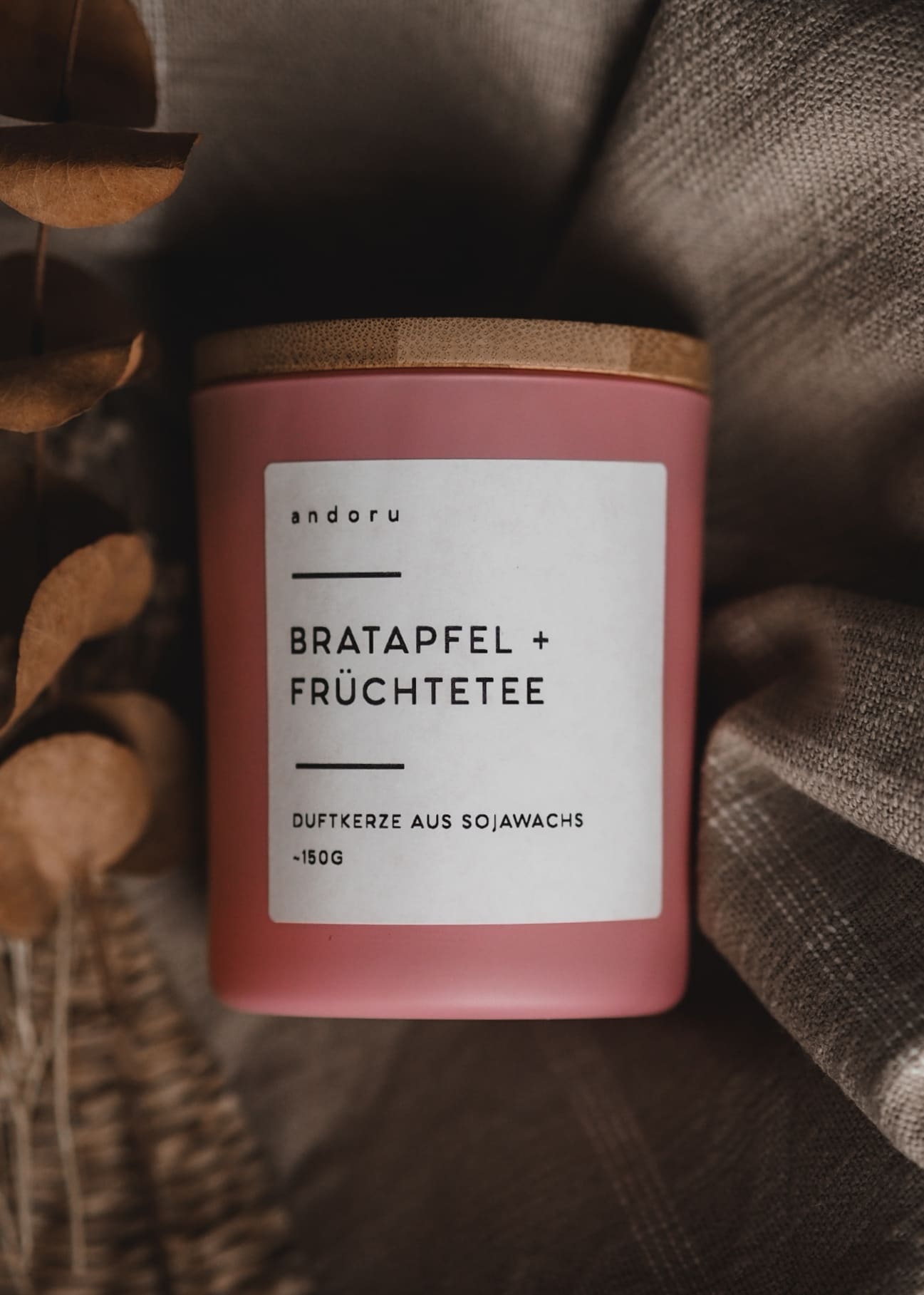 Duftkerze im rosa Glas mit Holzdeckel Bratapfel Früchtetee Duft liegend auf einer Decke