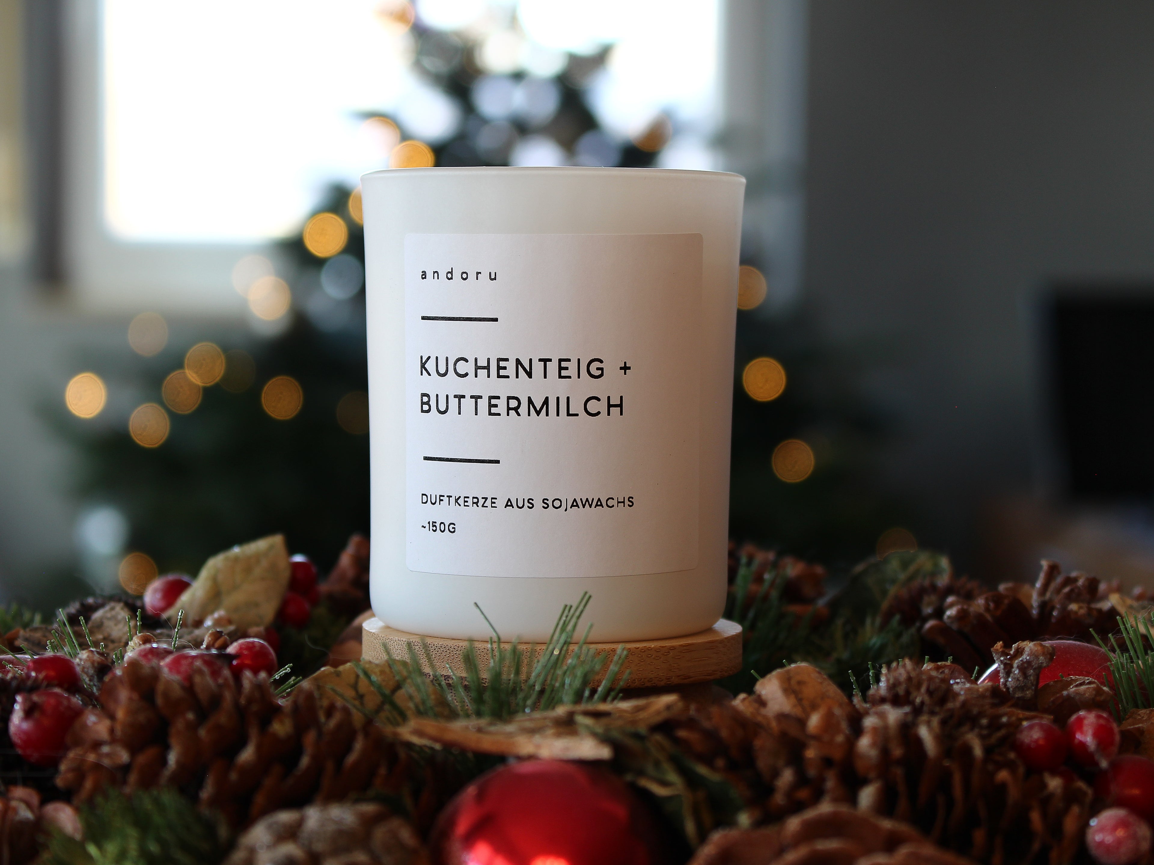 starke Duftkerze aus Deutschland weißes Glas mit Holzdeckel Kuchenteig Buttermilch mit Weihnachtsdeko und Tannenbaum im Hintergrund