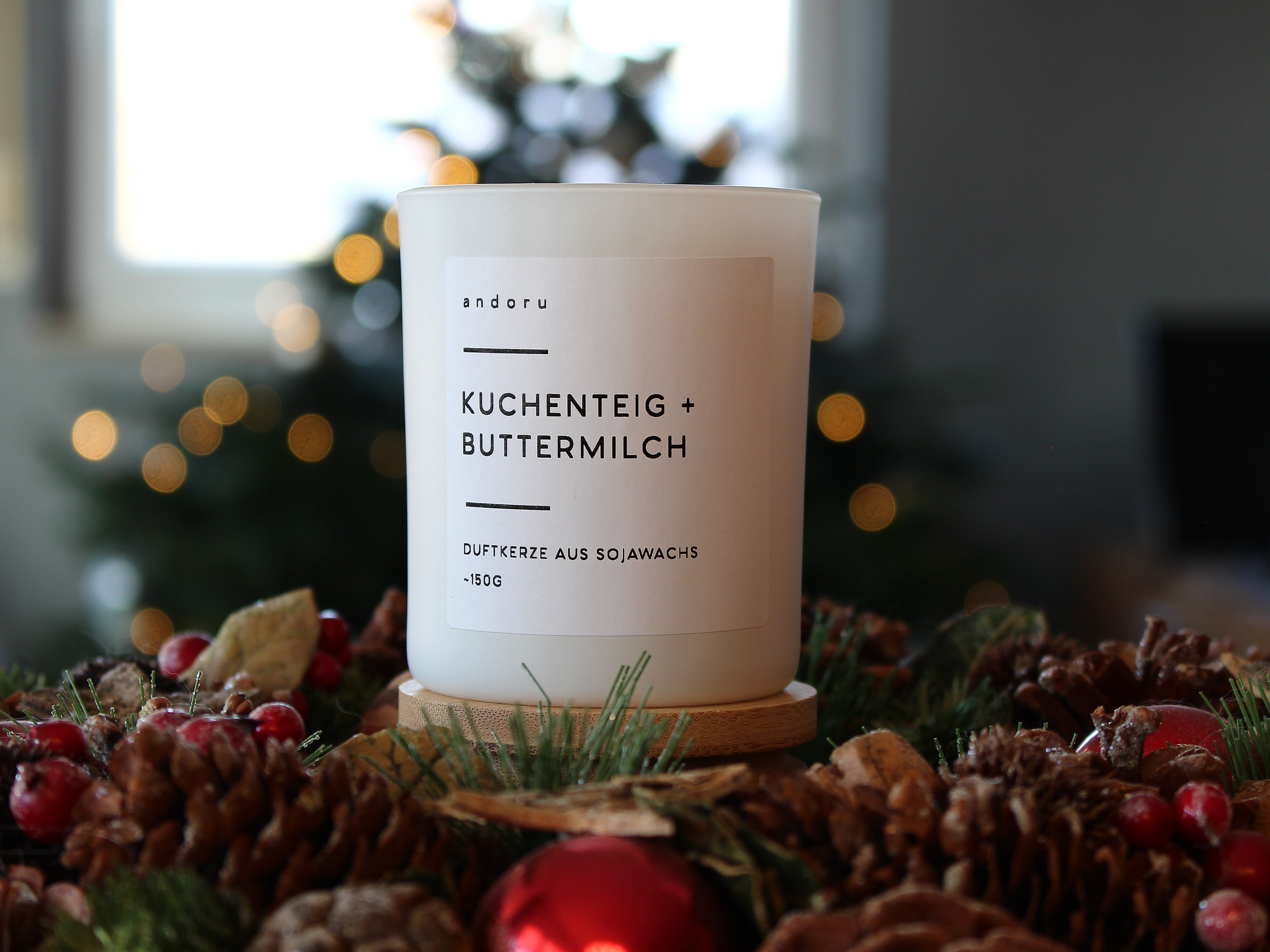 starke Duftkerze aus Deutschland weißes Glas mit Holzdeckel Kuchenteig Buttermilch mit Weihnachtsdeko und Tannenbaum im Hintergrund
